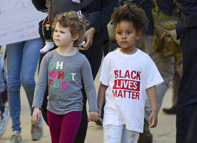 Children walk hand-in-hand as demonstrators protest the fatal shooting Sunday of an unarmed black man in Sacramento, Calif., Thursday, March 22, 2018. Hundreds of people rallied for Stephon Clark, a 22-year-old who was shot in his grandparents' backyard. Police say they feared he had a handgun when they confronted him after reports that he had been breaking windows, but he only had a cellphone. (AP Photo/Robert Petersen)