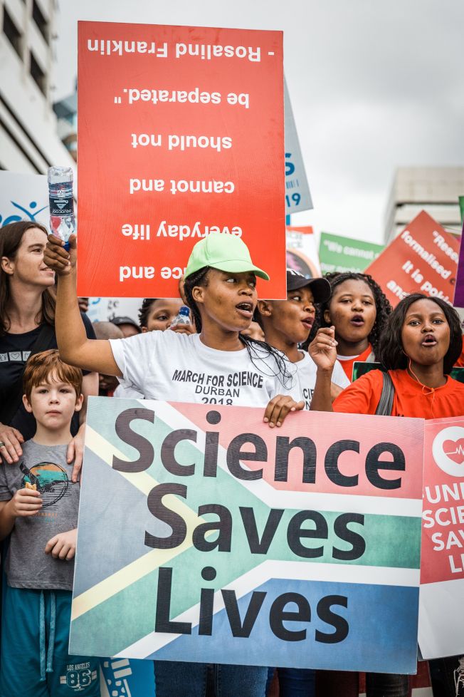 People holds up signs during the 'March for Science' in Durban on April 14, 2018, organised by the University of KwaZulu-Natal (UKZN), the South African Medical Research Council (SAMRC), the South African Medical Students Association (SAMSA), the Centre for the AIDS Programme of South Africa (CAPRISA), and Global Laboratories. / AFP PHOTO / RAJESH JANTILAL